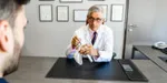 Le Dr Gazielly examine un modèle anatomique d'épaule avec un patient